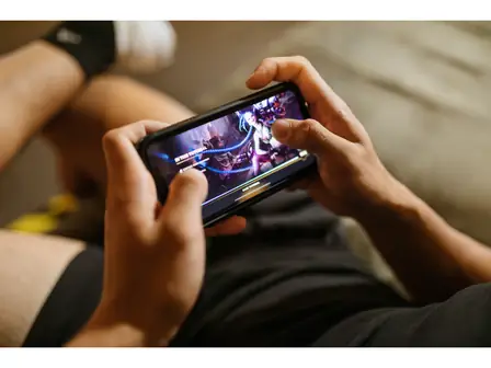 Hands holding a smartphone while playing a mobile game